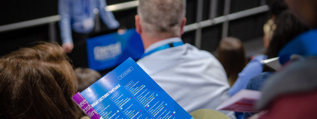 A delegate reads the programme during a lecture.