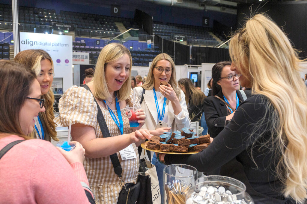 A group of delegates enjoy some free brownies from 2023 sponsor Atelier Dentistry.