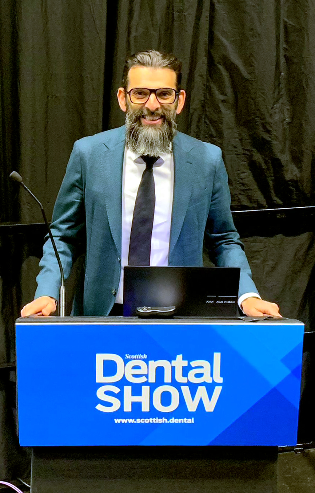 Tariq standing behind the podium at the Scottish Dental Show