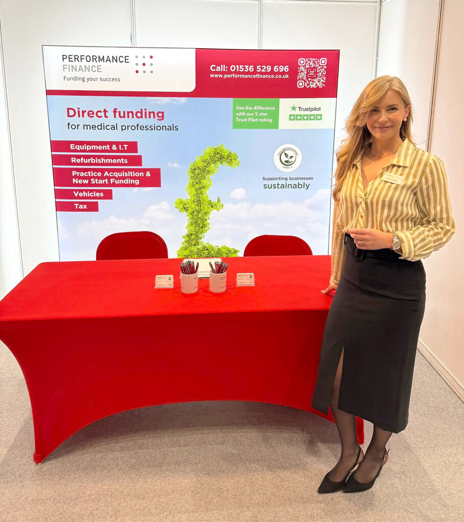 Susan stands to the right of a bright red exhibition table.